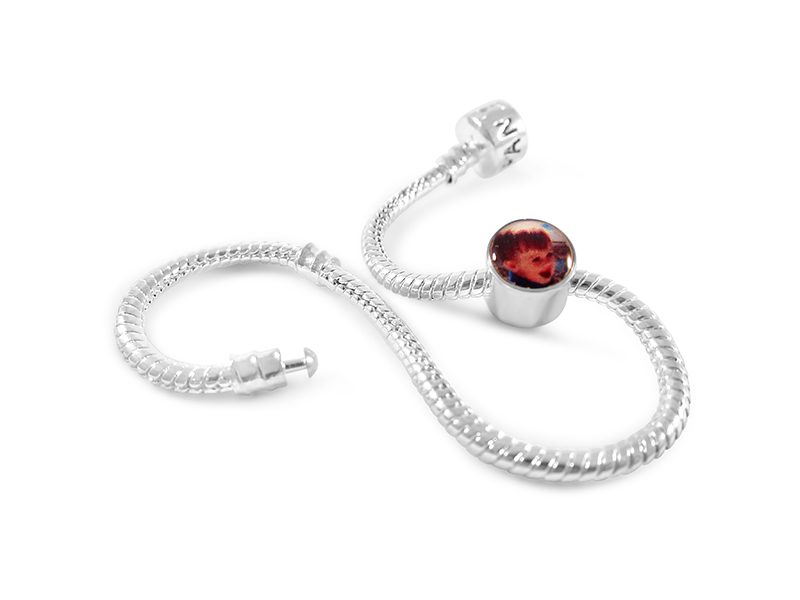 a silver bracelet with a red glass bead