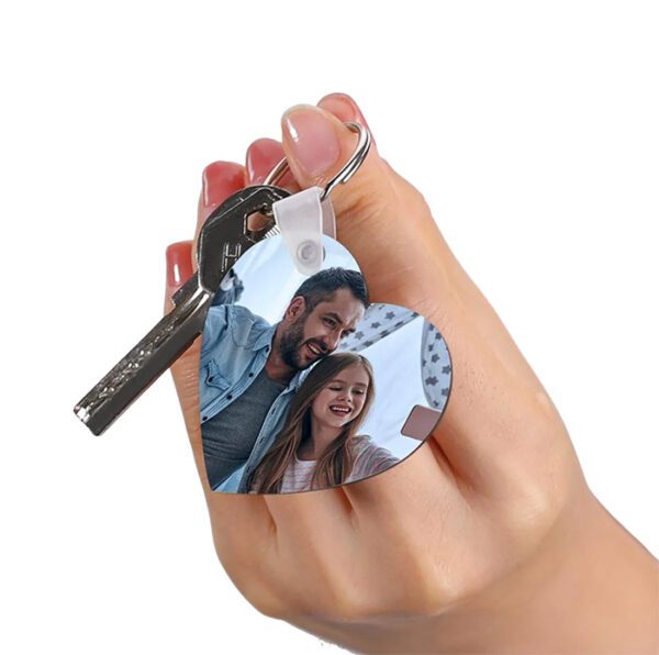 a hand holding a heart shaped photo keychain